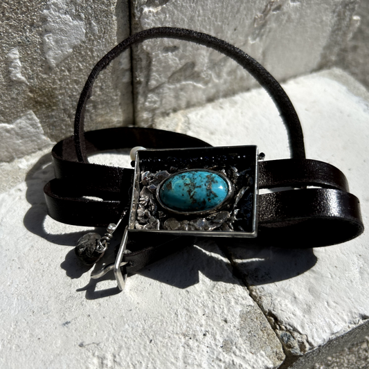 Conçu comme une véritable unité de fouille, ce bijou en argent 950 a été fondu et aggloméré sans soudure, créant une texture brute et chunky qui évoque les parois rocheuses d'un gisement. Au cœur de cette pièce se trouve une magnifique turquoise de Perse. Délicat filet de perles en blue sandstone s'étire le long de la paroi, Sur le côté, des artefacts anciens sont suspendus par un fil d'argent : une perle d'eau et une vénus de willendorf en céramique.