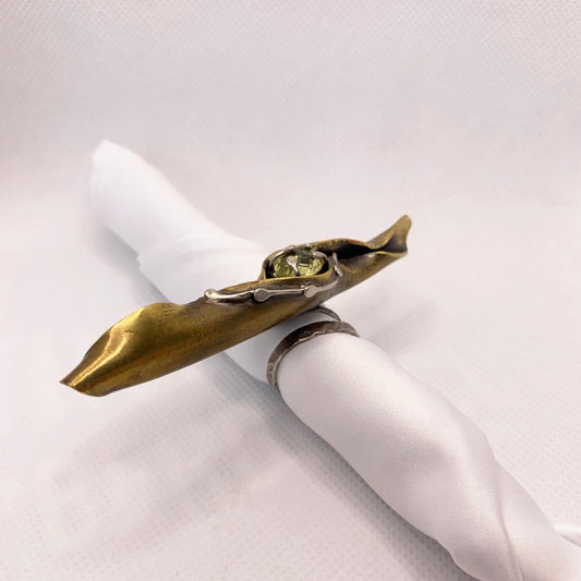 Bague en laiton forgé comme une feuille d'arbuste enroulée par le vent, elle couvre 4 doigts, repose sur un jonc réglable en laiton. En son cœur repose un serti en argent avec un quartz jaune facetté. Vue de profil