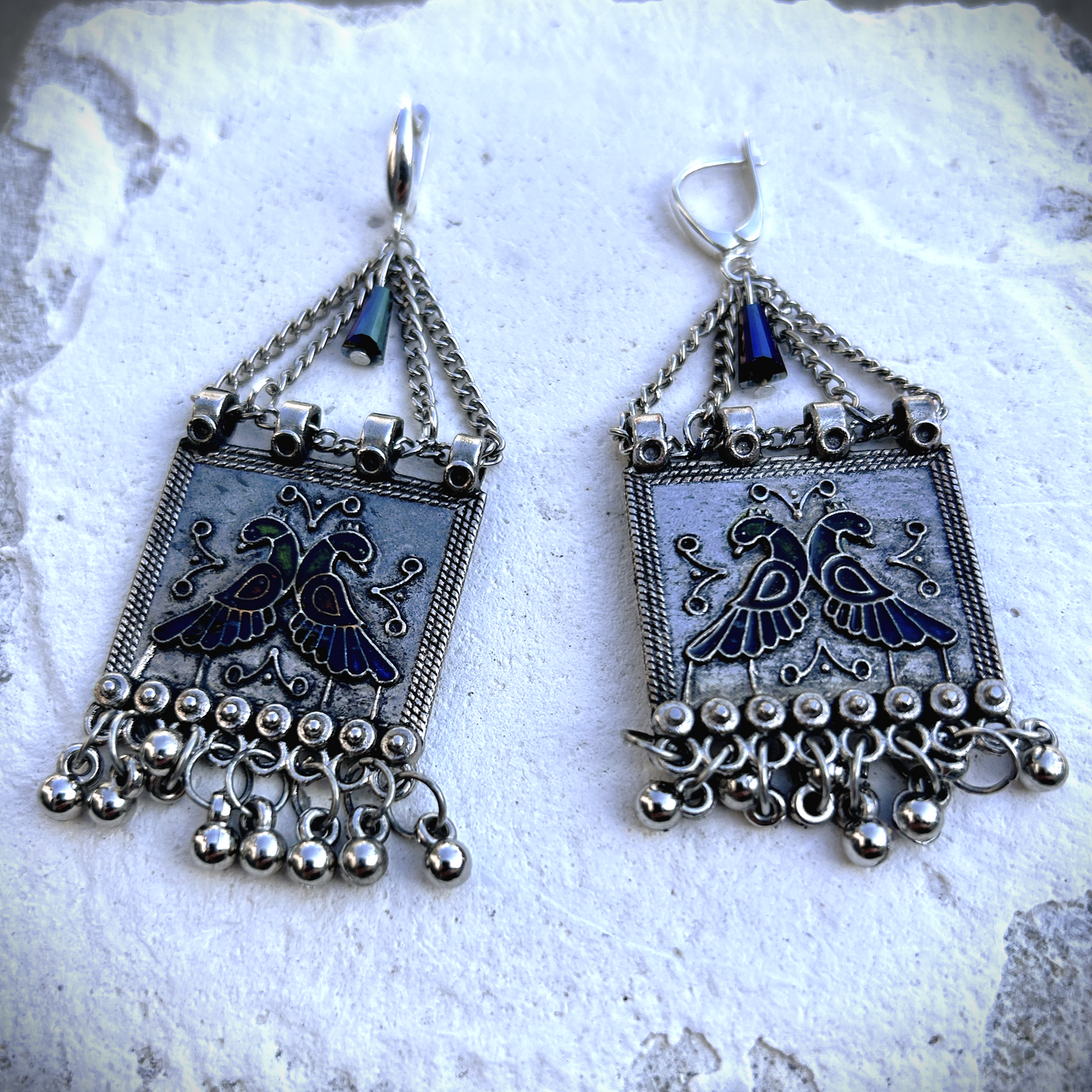 Boucles sur crochets sécurité en argent 950, composées d'un jeu de chainettes auxquelles  est suspendu une plaque de métal décoré de deux paons (cloisonné et pâte de verre). J'ai suspendu des pampilles récupéré sur un vieux collier indien.  jApreès avoir retiré la rouille, je les ai noirci à la peinture métal, puis brossé à la brosse acier. Elles sont protégé à la cire. Je voulais  créer d'inspiration indienne avec ce couple de paon aux couleurs chatoyantes vertes, bleues et rouges