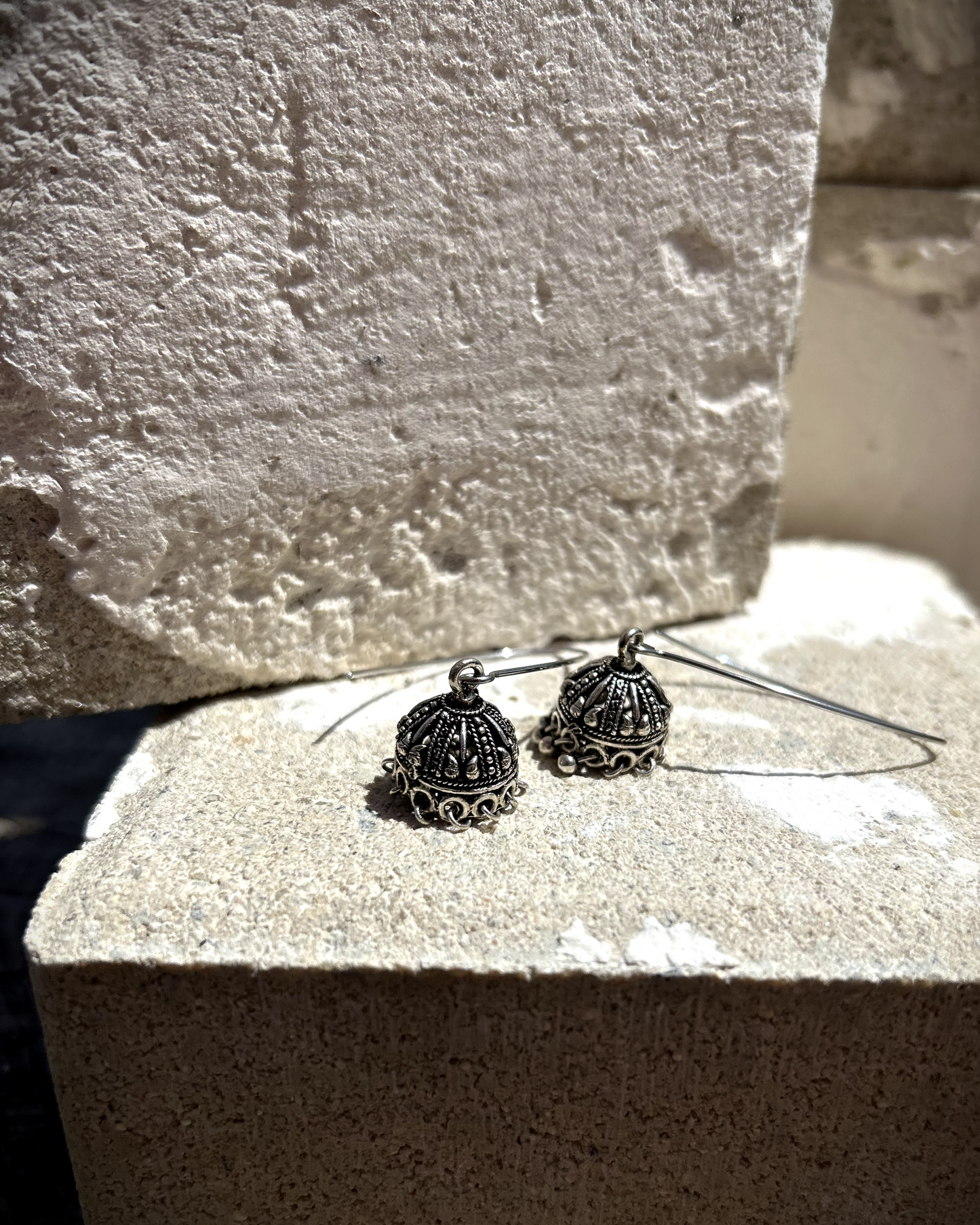 Deux boucles d’une simplicité absolue, réalisées à partir d’un crochet en inox en V, sur lequel j’ai suspendu un charme récupéré d’une paire de boucles d’oreilles indiennes de mariage. J’ai recomposé certaines pampilles disparues grâce à des tiges en acier inoxydable. Un équilibre parfait entre douceur et un parfum d’ailleurs. Vue de dessus