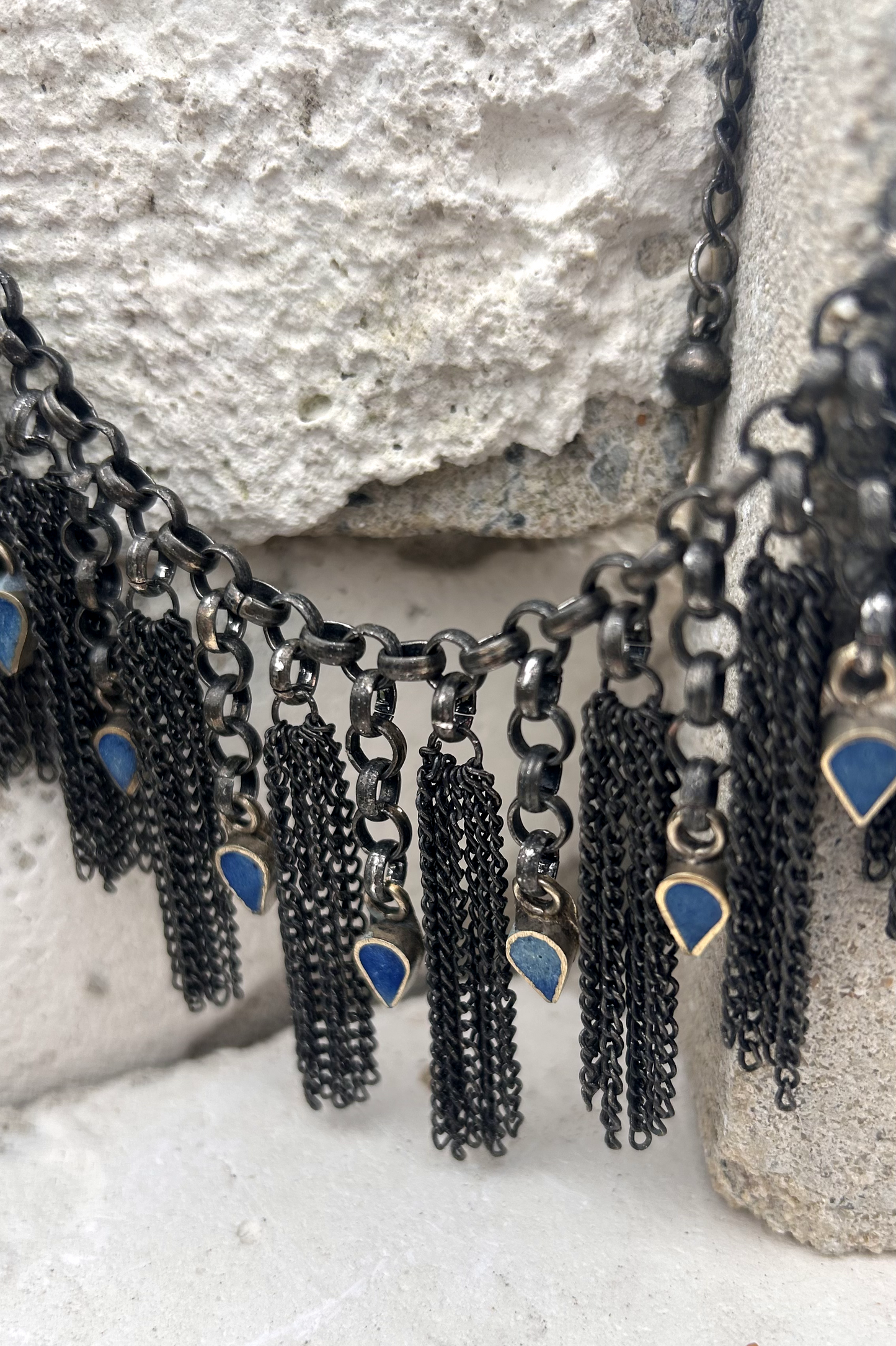 Collier en inox réalisé à de vieux maillons d'un collier cascade, de pampilles de chaines d'un collier de pampilles et de pendants en pate de verre bleu d'un vieux collier d'Essaouira.  Vue de près.