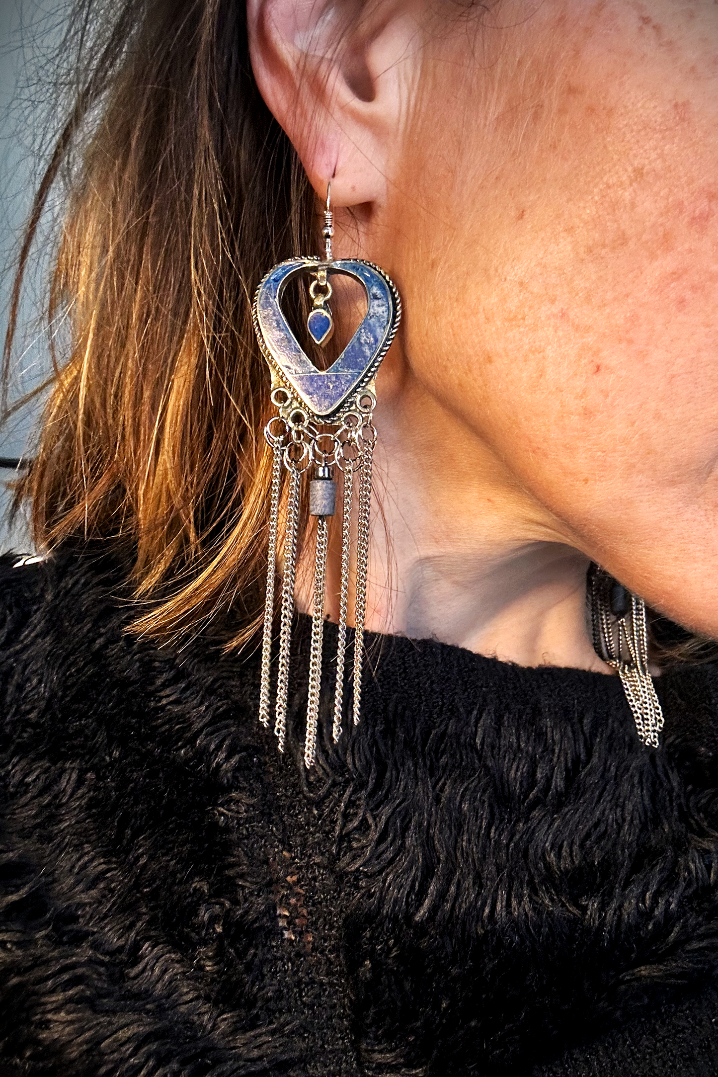 Boucles d'oreilles longues réalisées à partir de deux pendentif coeur d'un vieux collier d'Essaouira, sciées, limées, émerisé, polies et entièrement vernies, y comris la pate de verre bleu sertie dans le cloisonné. Dessous j'ai gardé qelques attaches pour construire un jeu d'anneau en inox auxquels j'ai supsendu des chaines et deux perles (une hématite, et une perle en pierre bleue). Au centre du coeur j'ai suspendu un petit charme du colllier pour illustrer les larmes du coeur. Vue portées.