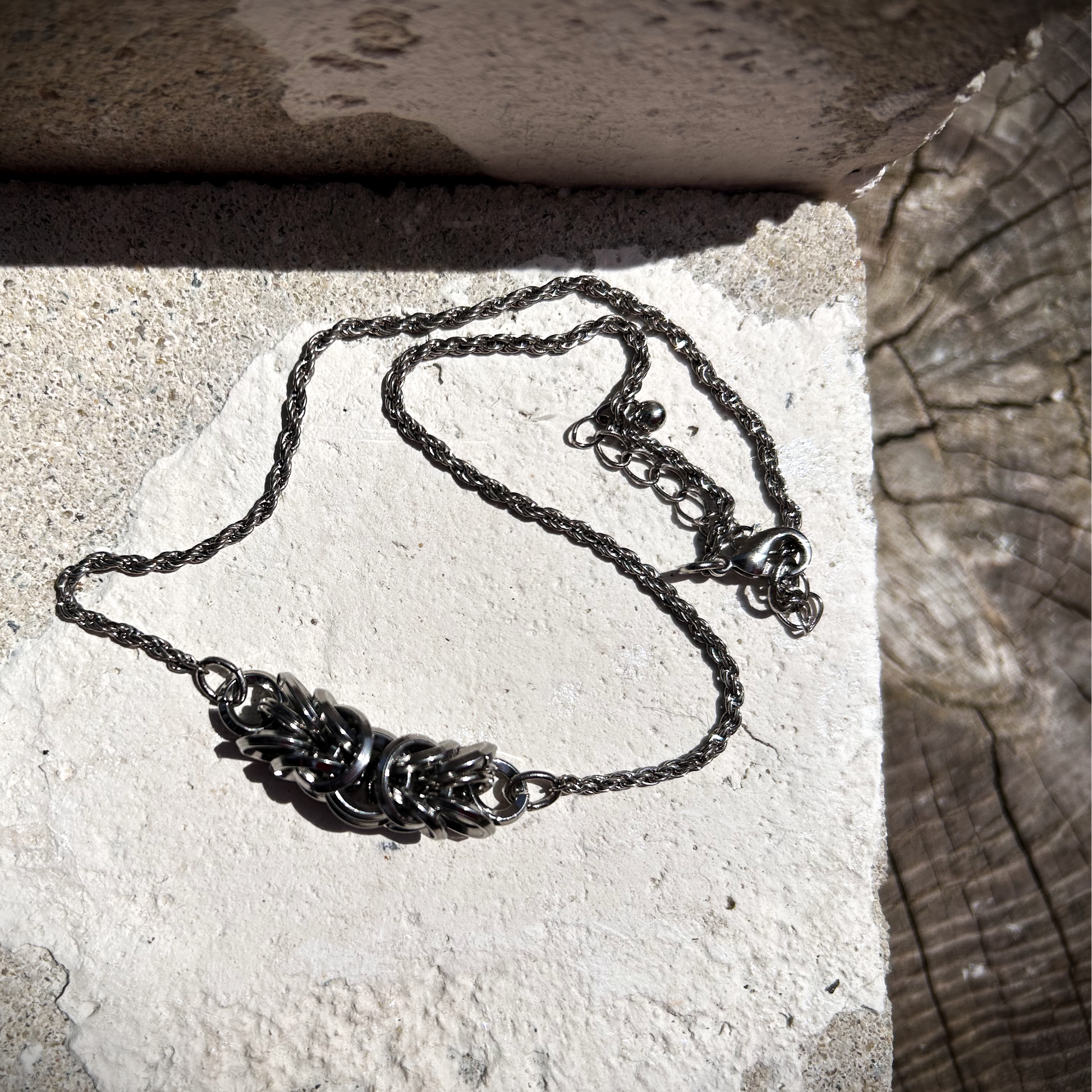 Ce collier ras-de-cou est composé d'une chaîne torsadée en acier inoxydable, récupérée sur un collier vintage avec médaillon central, au centre de laquelle j'ai intégré trois centimètres de maille byzantine.

J'ai soigneusement assemblé et structuré cette maille, appelée byzantine, à partir d'anneaux en acier inoxydable 304 (8 × 1,8 mm et 10 × 1,8 mm), préformés et sélectionnés pour leur solidité et leur finition biseautée.