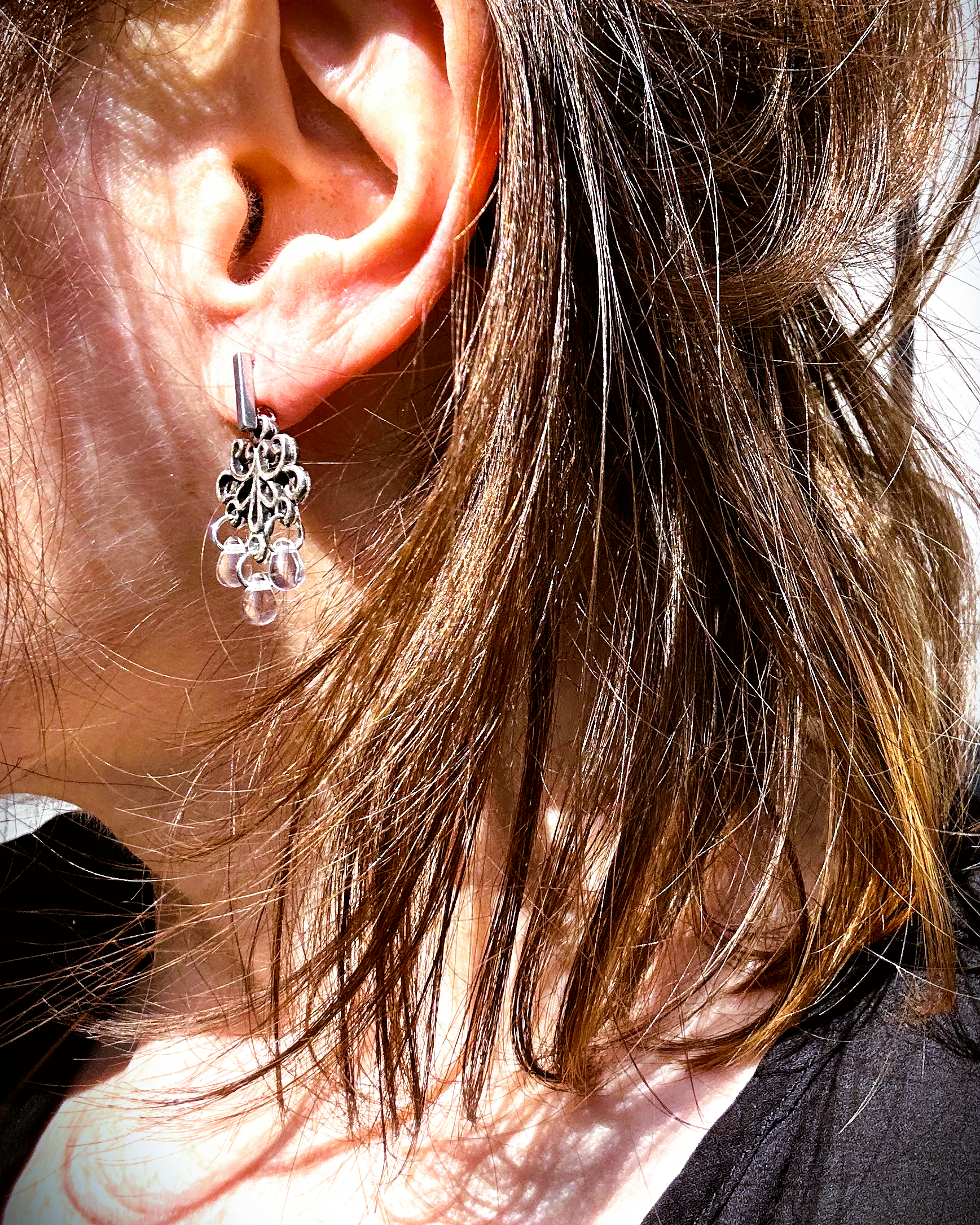 Boucles d'oreilles façonnée à partir de deux arabesques métalliques d'un vieux bracelet ottoman, montées sur des puces rectangulaires en inox hypoallergénique.

J'adore ces volutes figées dans le temps, comme une danse capturée dans le métal. Pour ajouter une touche éthérée et sophistiquée, j'ai suspendu de petites "gouttes d’eau" en verre translucide, apportant légèreté et mouvement aux boucles. Vue portée.