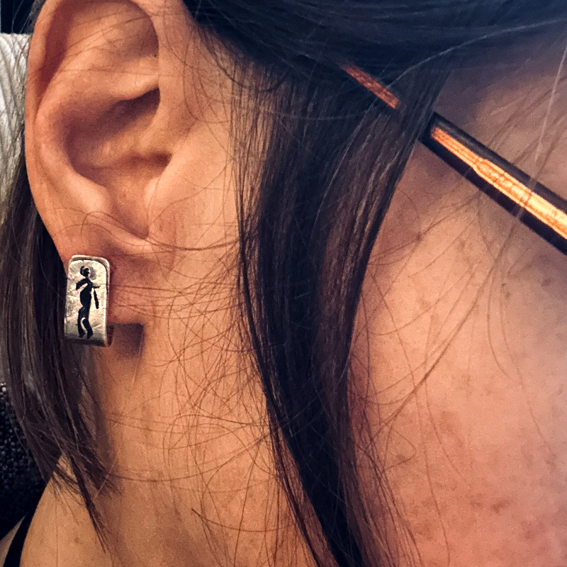 Boucles d'oreilles formes agrafes en argent texturés, parsemés de symboles rupestres ajourés et oxydés. Attache traversante avec poussoir silicone