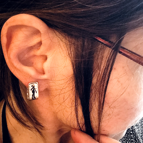 Boucles d'oreilles formes agrafes en argent texturés, parsemés de symboles rupestres ajourés et oxydés. Attache traversante avec poussoir silicone