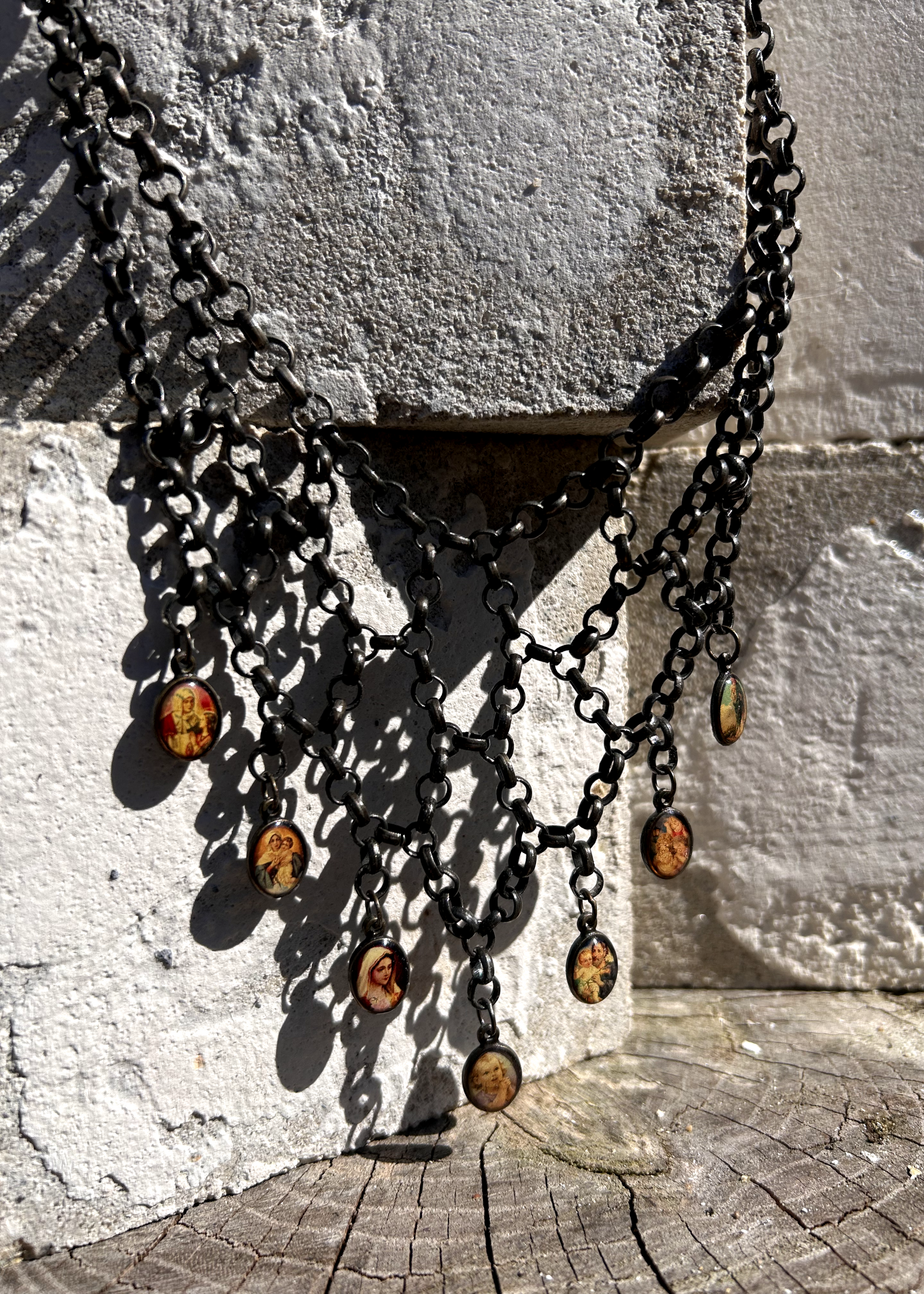 pièce unique, façonnée à partir de bijoux anciens soigneusement sélectionnés, nettoyés et réassemblés pour transmettre un message puissant:
Sept médailles religieuses vintage au fond jauni (Saints, Chérubin, Vierge), serties dans du laiton, issues d’un ancien collier de perles de culture.
Des anneaux en inox, récupérés un à un sur un collier cascade, assemblés pour créer un plastron pyramidal.