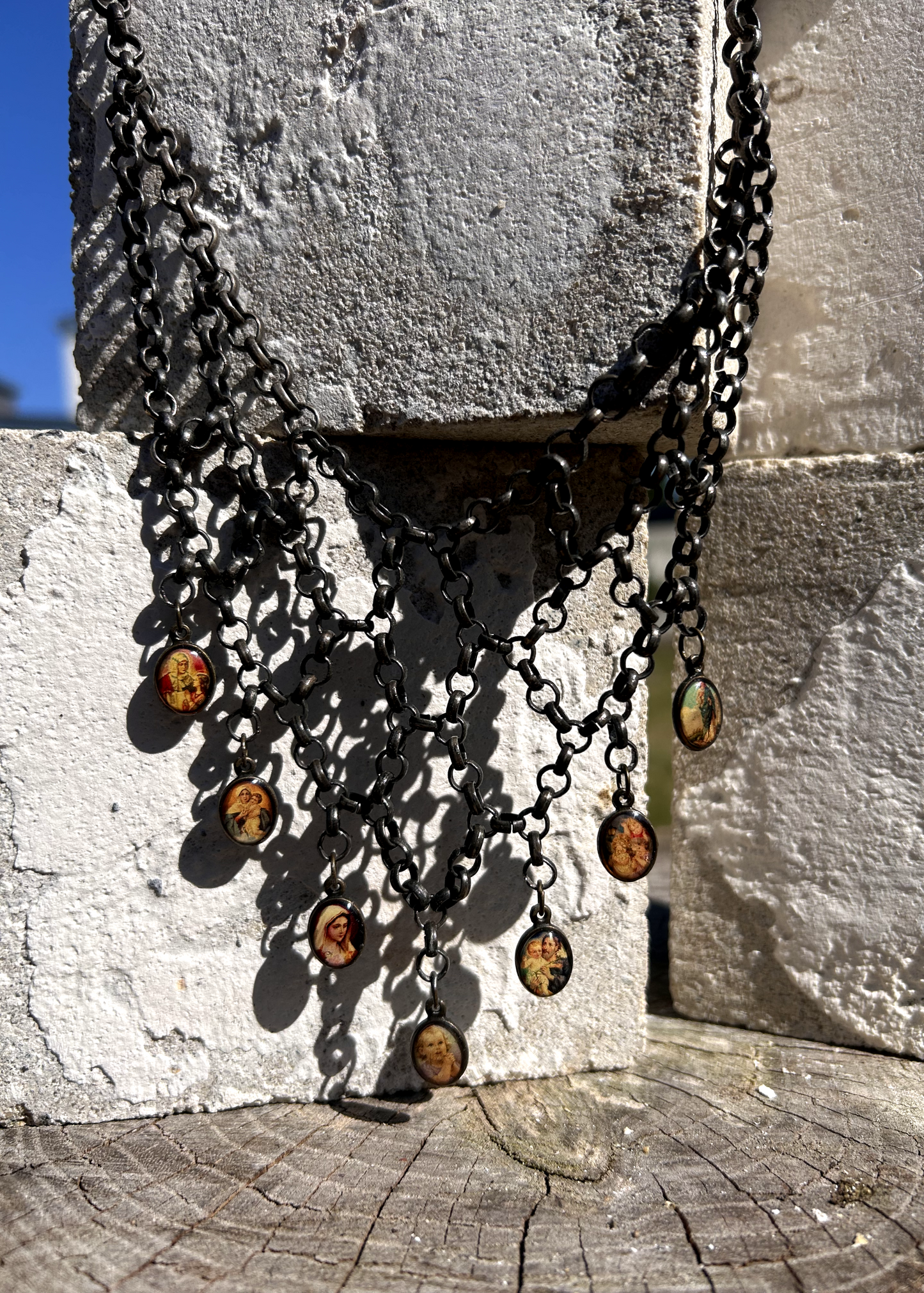 pièce unique, façonnée à partir de bijoux anciens soigneusement sélectionnés, nettoyés et réassemblés pour transmettre un message puissant:

Sept médailles religieuses vintage au fond jauni (Saints, Chérubin, Vierge), serties dans du laiton, issues d’un ancien collier de perles de culture.
Des anneaux en inox, récupérés un à un sur un collier cascade, assemblés pour créer un plastron pyramidal.