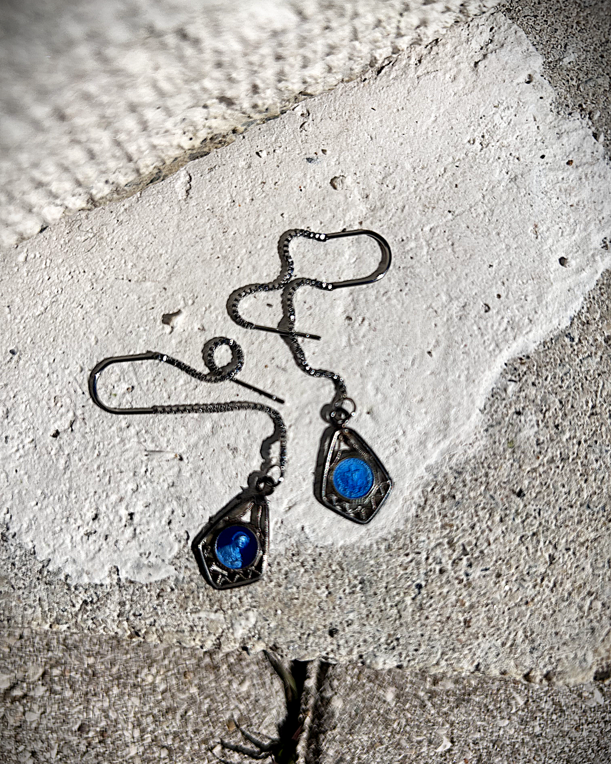 Petites boucles d’oreilles légères, composées d’une chaîne en inox hypoallergénique, suspendue à un U en inox qui traverse le lobe. À son extrémité, une médaille en métal bleu émaillée représentant la Vierge Marie est délicatement accrochée.