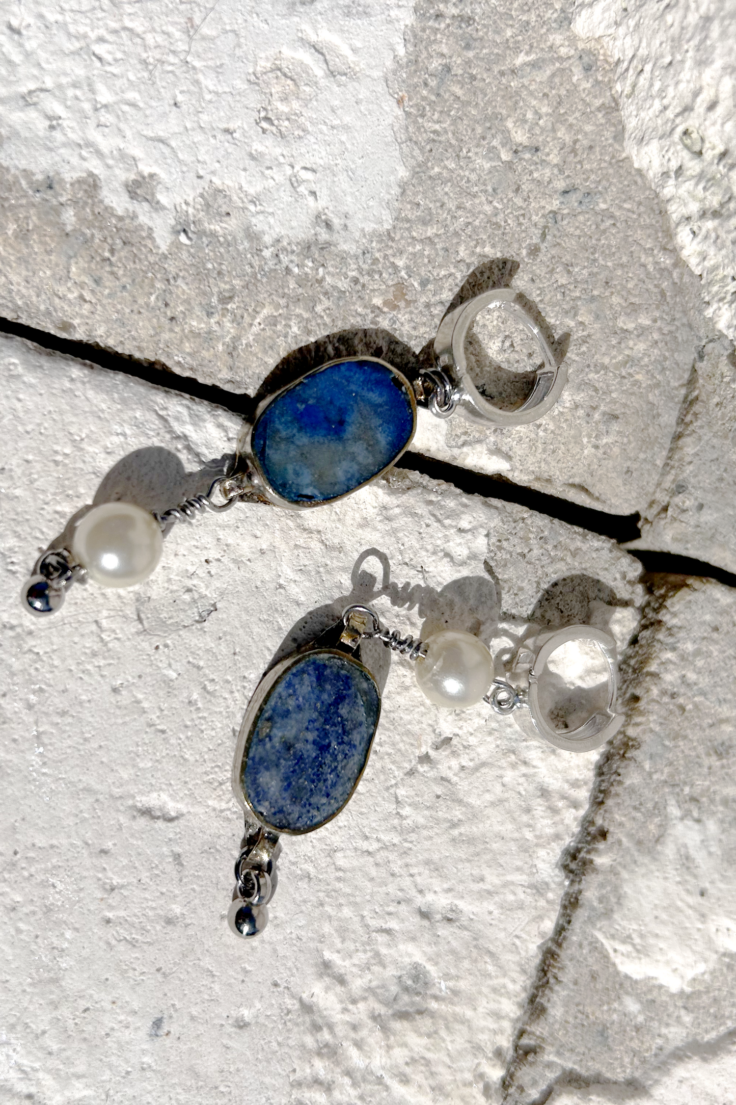 Paire de boucles d'oreilles composées d'une pâte de verre sertie en laiton, provenant d'un vieux collier d'Essaouira, de perles de culture issues d'un ancien collier de ma grand-mère, de deux anneaux en argent 925 à clipser à l'oreille (non soudés, conformément à la loi), de tiges en inox 316L torsadées et d'une pampille provenant d'un collier indien. Vue de face. Les éléments sont volontairement intervertis à chaque oreille, mais restent de même longueur.