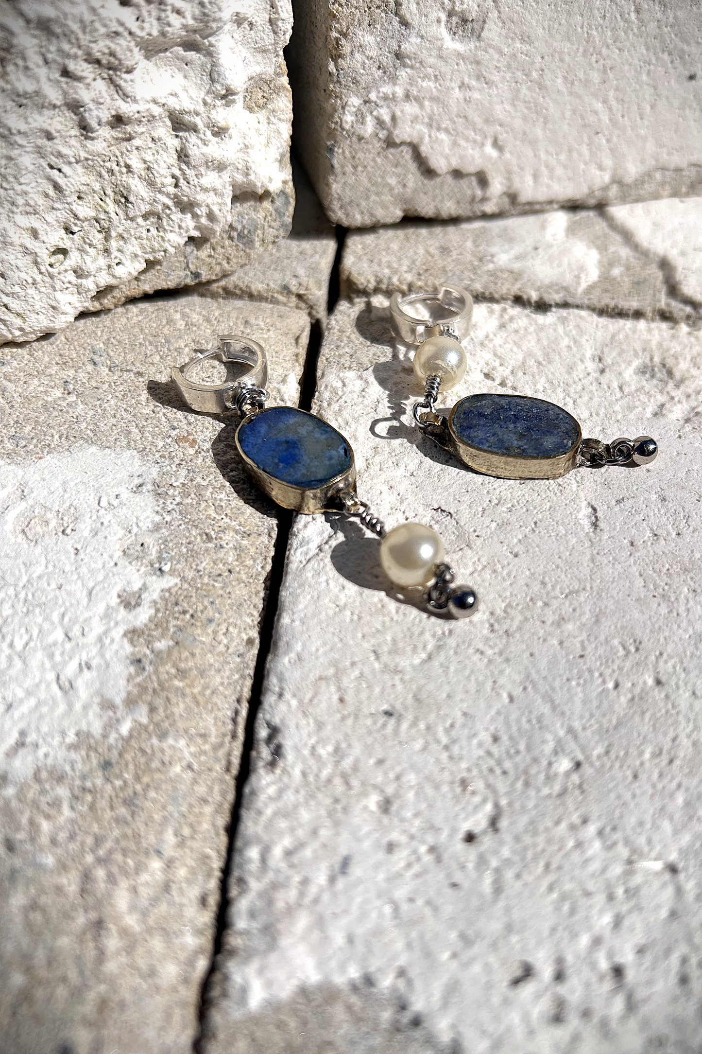 Paire de boucles d'oreilles composées d'une pâte de verre sertie en laiton, provenant d'un vieux collier d'Essaouira, de perles de culture issues d'un ancien collier de ma grand-mère, de deux anneaux en argent 925 à clipser à l'oreille (non soudés, conformément à la loi), de tiges en inox 316L torsadées et d'une pampille provenant d'un collier indien. Vue de profil. Les éléments sont volontairement intervertis à chaque oreille, mais restent de même longueur.