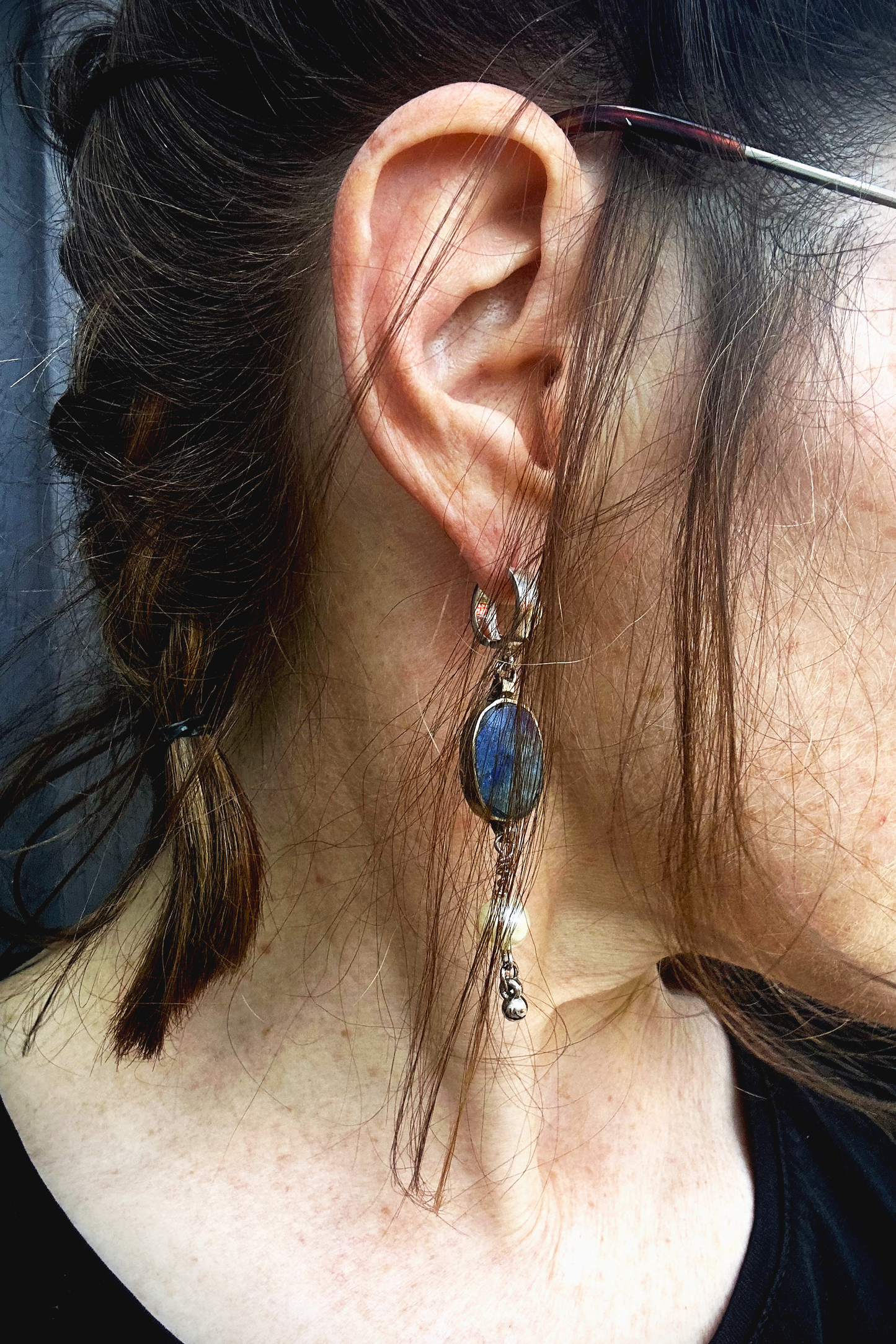 Paire de boucles d'oreilles composées d'une pâte de verre sertie en laiton, provenant d'un vieux collier d'Essaouira, de perles de culture issues d'un ancien collier de ma grand-mère, de deux anneaux en argent 925 à clipser à l'oreille (non soudés, conformément à la loi), de tiges en inox 316L torsadées et d'une pampille provenant d'un collier indien. Vue de portée. Les éléments sont volontairement intervertis à chaque oreille, mais restent de même longueur.