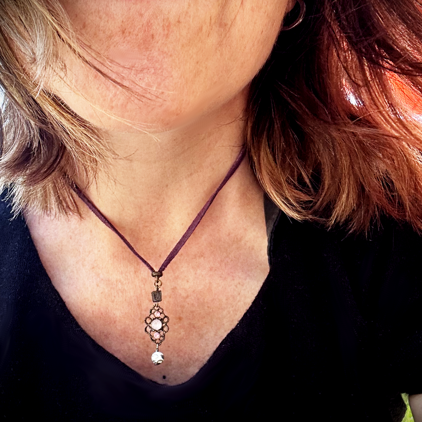 Vieux collier en suédine violette, sublimé par un charme dans les mêmes tons, récupéré sur un bijou ancien. J’ai ajouté deux perles : une perle japonaise en métal et une perle de verre aux tonalités délicates des cerisiers en fleurs. Tout en douceur, un brin vintage, comme un souffle léger parmi les pétales dansants des sakura. Vue porté.