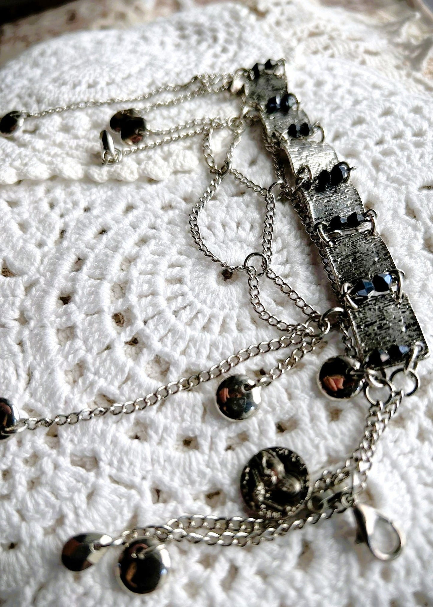 Ce bracelet est une pièce unique, façonnée avec à partir de matériaux chinés puis, soigneusement sélectionnés : Chainettes récupérés sur des pampilles d'un collier berbère
Carrés de métal inconnu récupérés sur un collier berbère, brossés puis courbés. Petits maillons en inox neufs, ajoutés pour relier les gros maillons et alléger l’ensemble. Perles double cône losange noires et bleutés brillantes récupérés sur un collier de franges de perles, fixés sur tiges en inoxydable. Fermoir menotte. Vue de profil