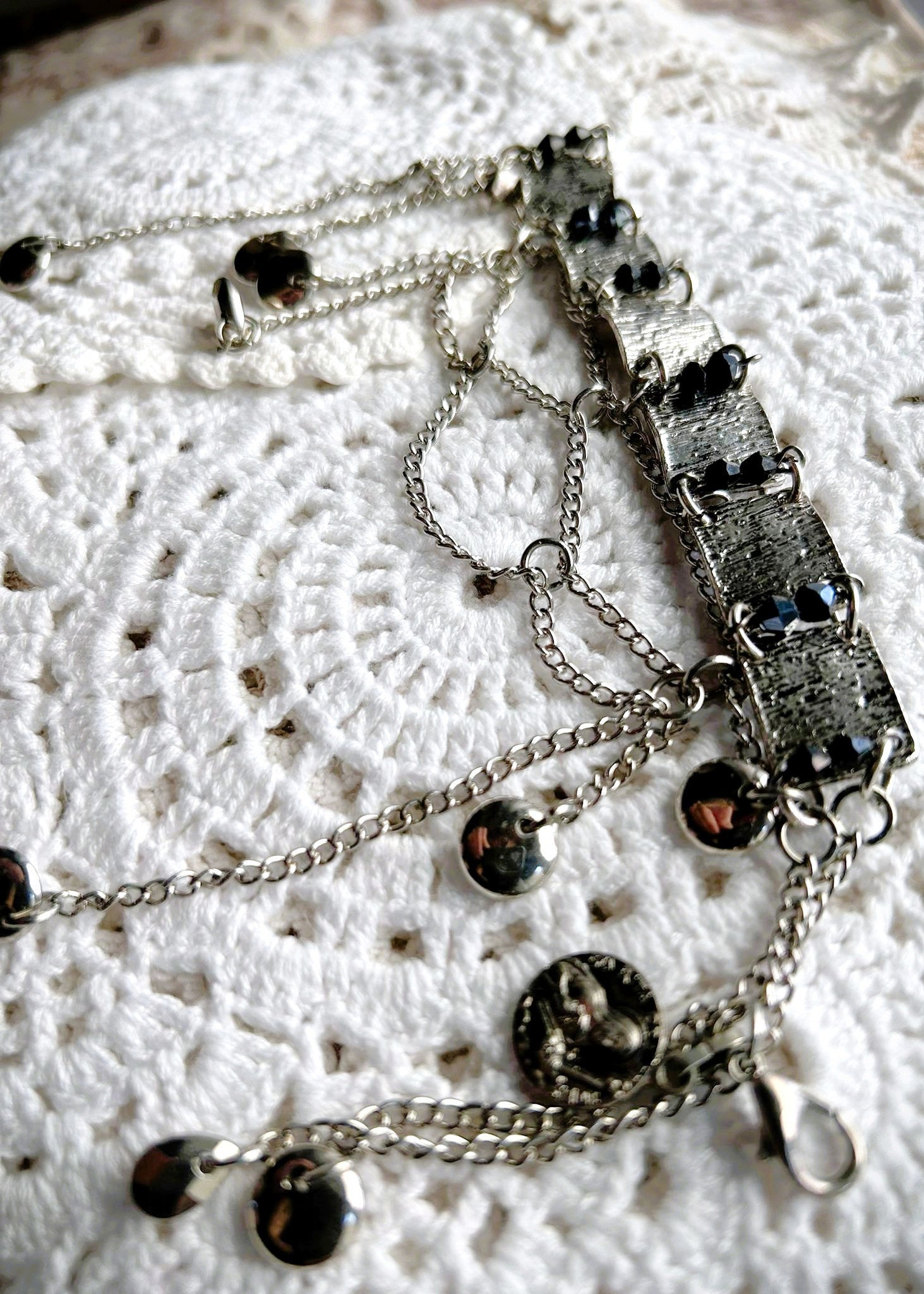 Ce bracelet est une pièce unique, façonnée avec à partir de matériaux chinés puis, soigneusement sélectionnés : Chainettes récupérés sur des pampilles d'un collier berbère
Carrés de métal inconnu récupérés sur un collier berbère, brossés puis courbés. Petits maillons en inox neufs, ajoutés pour relier les gros maillons et alléger l’ensemble. Perles double cône losange noires et bleutés brillantes récupérés sur un collier de franges de perles, fixés sur tiges en inoxydable. Fermoir menotte. Vue de profil