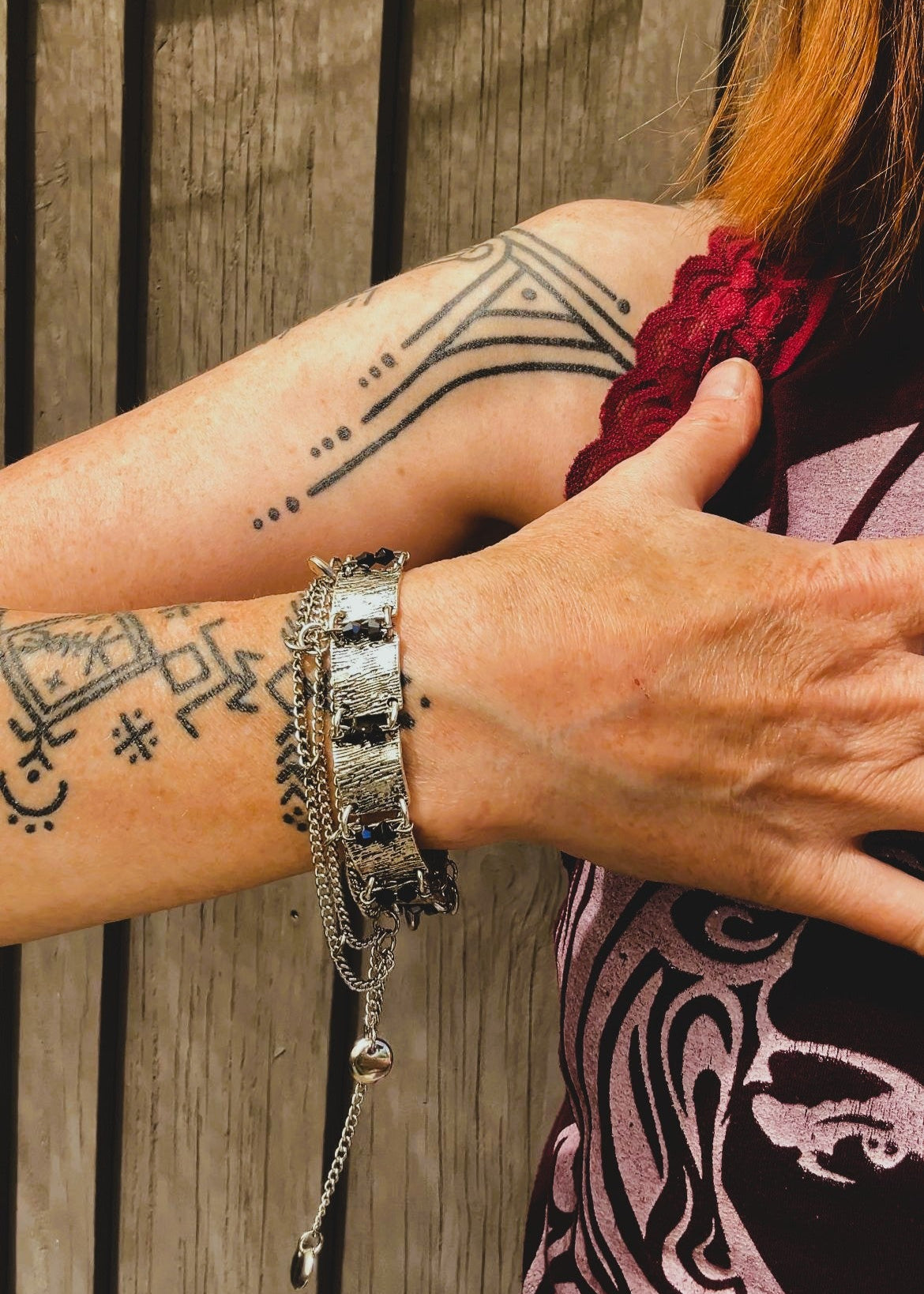 Ce bracelet est une pièce unique, façonnée avec à partir de matériaux chinés : Chainettes et carrés de métal inconnu récupérés sur un collier berbère, brossés puis courbés. Petits maillons en inox  pour alléger l’ensemble. Perles double cône losange noires et bleutés brillantes récupérés, fixés sur tiges en inoxydable. Fermoir menotte. Vue bracelet porté au poignet.