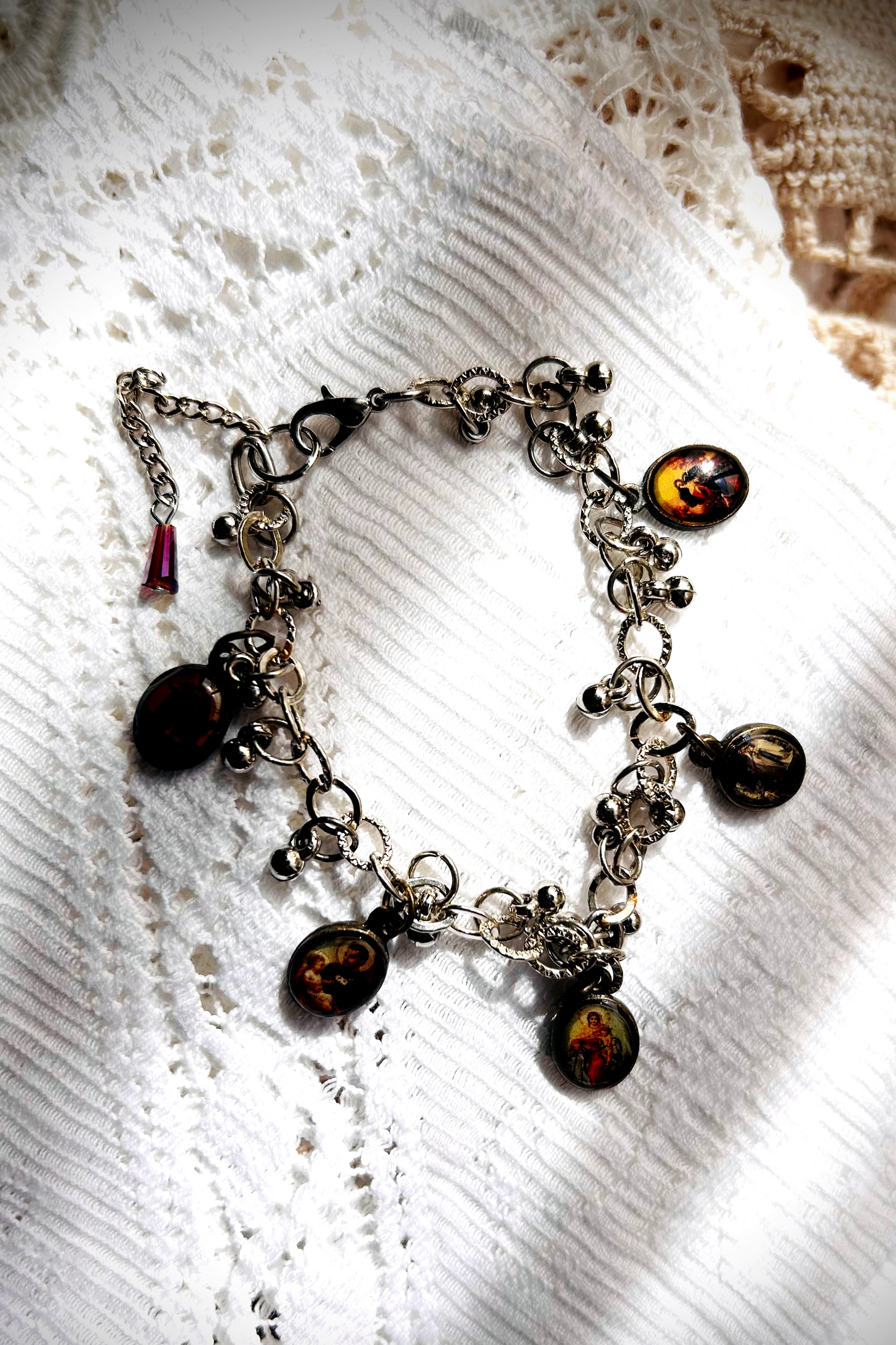 Bracelet recyclé d'un collier, agrémenté de pampilles indiennes, et de médailles religieuses de Saints. J'ai accroché une perle rouge au fermoir, au Japon  Le rouge protège contre les mauvais esprits et les maladies.