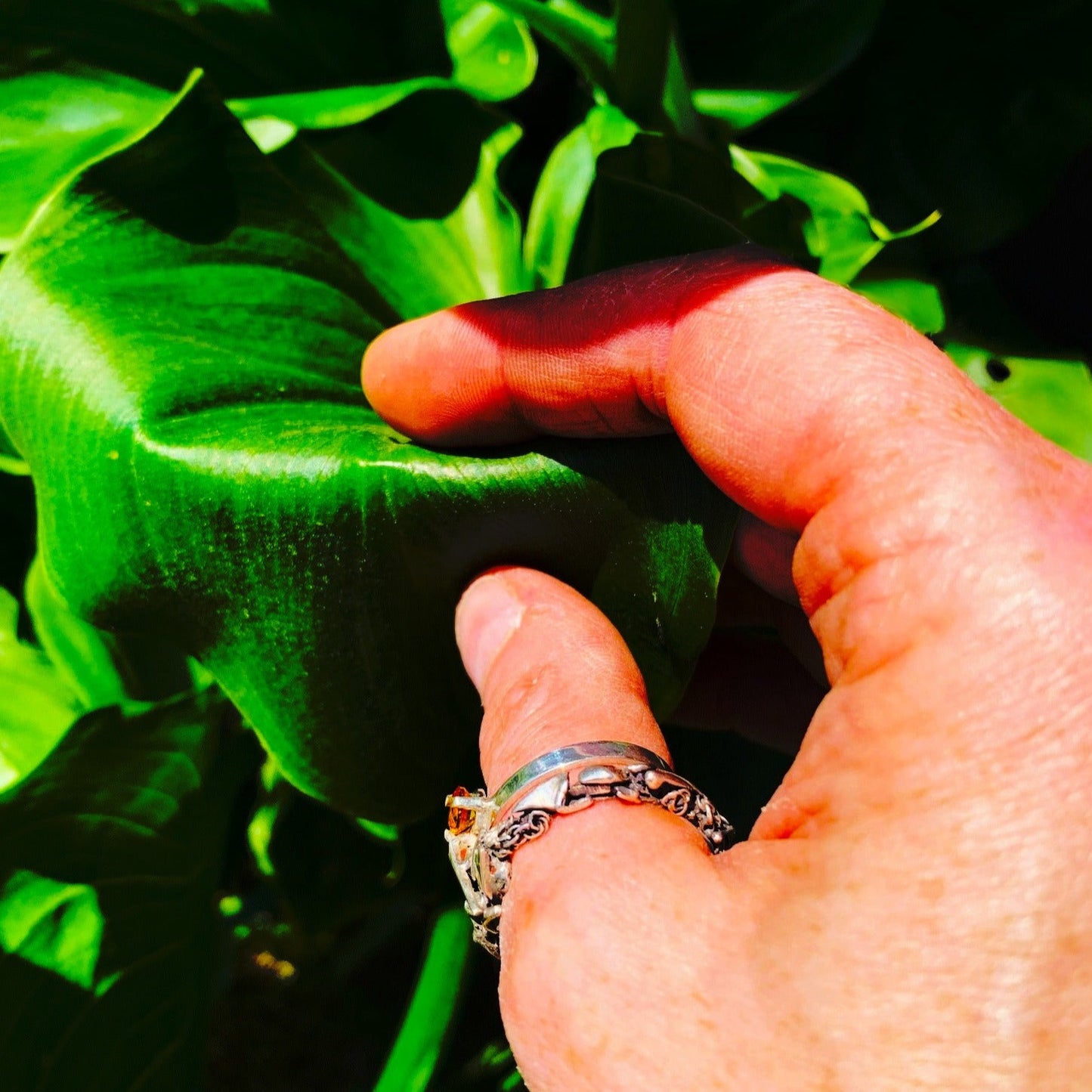 Inspirée par les couronnes de fleurs de Tahiti, cette bague évoque le Lei, symbole de l'Aloha hawaïen. Elle se compose de deux joncs : un petit en taille 62 avec une citrine de 5 mm, porté côté main, et un jonc plus large pour le pouce, constitué de morceaux d'argent travaillés. Les deux joncs sont reliés par un pont en forme de tige de plante, vue portée de dessus.