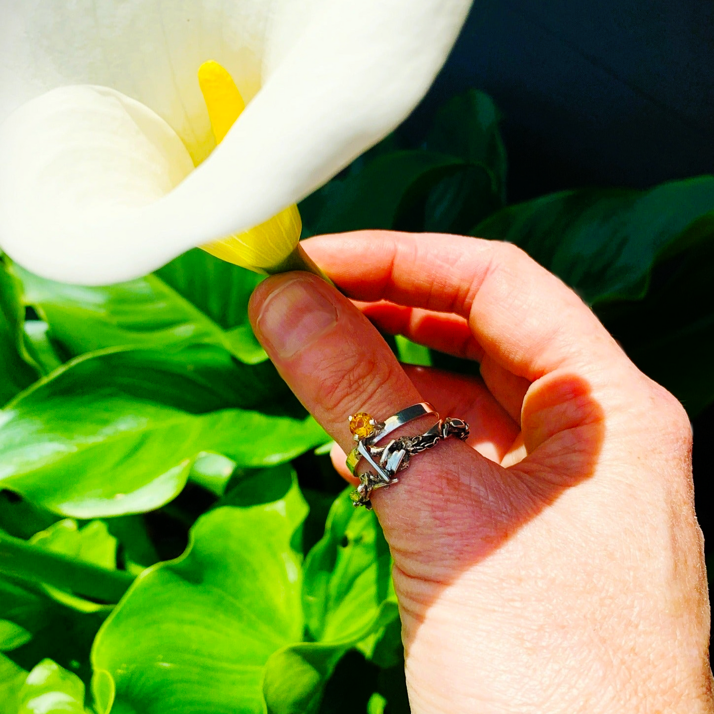 Inspirée par les couronnes de fleurs de Tahiti, cette bague évoque le Lei, symbole de l'Aloha hawaïen. Elle se compose de deux joncs : un petit en taille 62 avec une citrine de 5 mm, porté côté main, et un jonc plus large pour le pouce, constitué de morceaux d'argent travaillés. Les deux joncs sont reliés par un pont en forme de tige de plante, Vue portée de dessus.