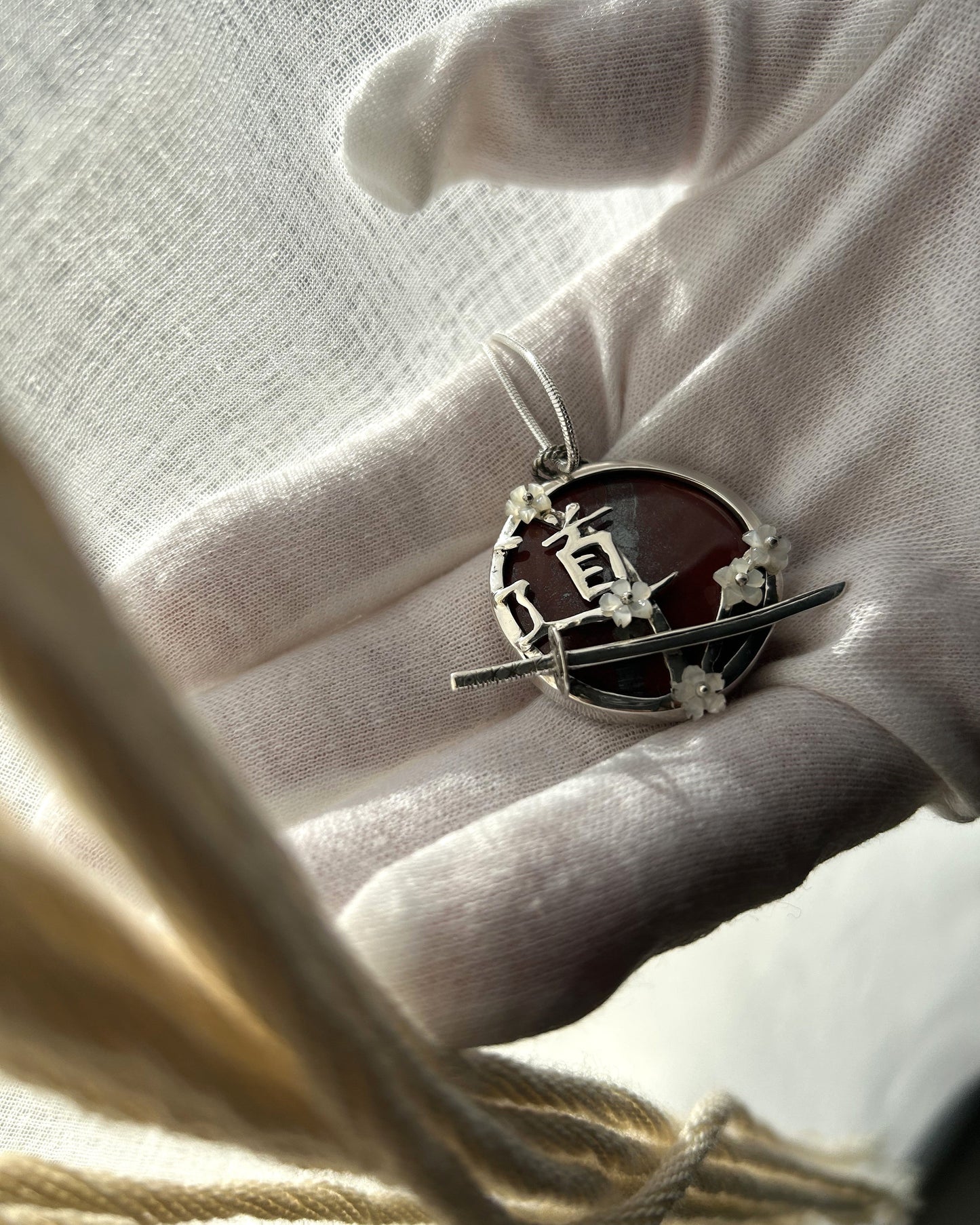 pendentif en argent avec sabre de l'iaido, fleurs de sakura en nacre, symbole du Do en japonais. Vue de dessus. Collier maille serpent.