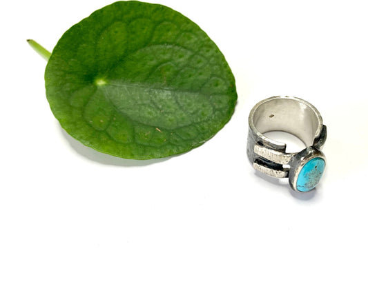 Bague en argent épaisse et martelée, inspirée du design des bracelets de force, sertie d'une turquoise d'Iran. Le serti repose sur deux bandes d'argent soudées, intégrées dans la continuité du jonc, assurant ainsi sa fermeture. Taille 59, vue de dessus.