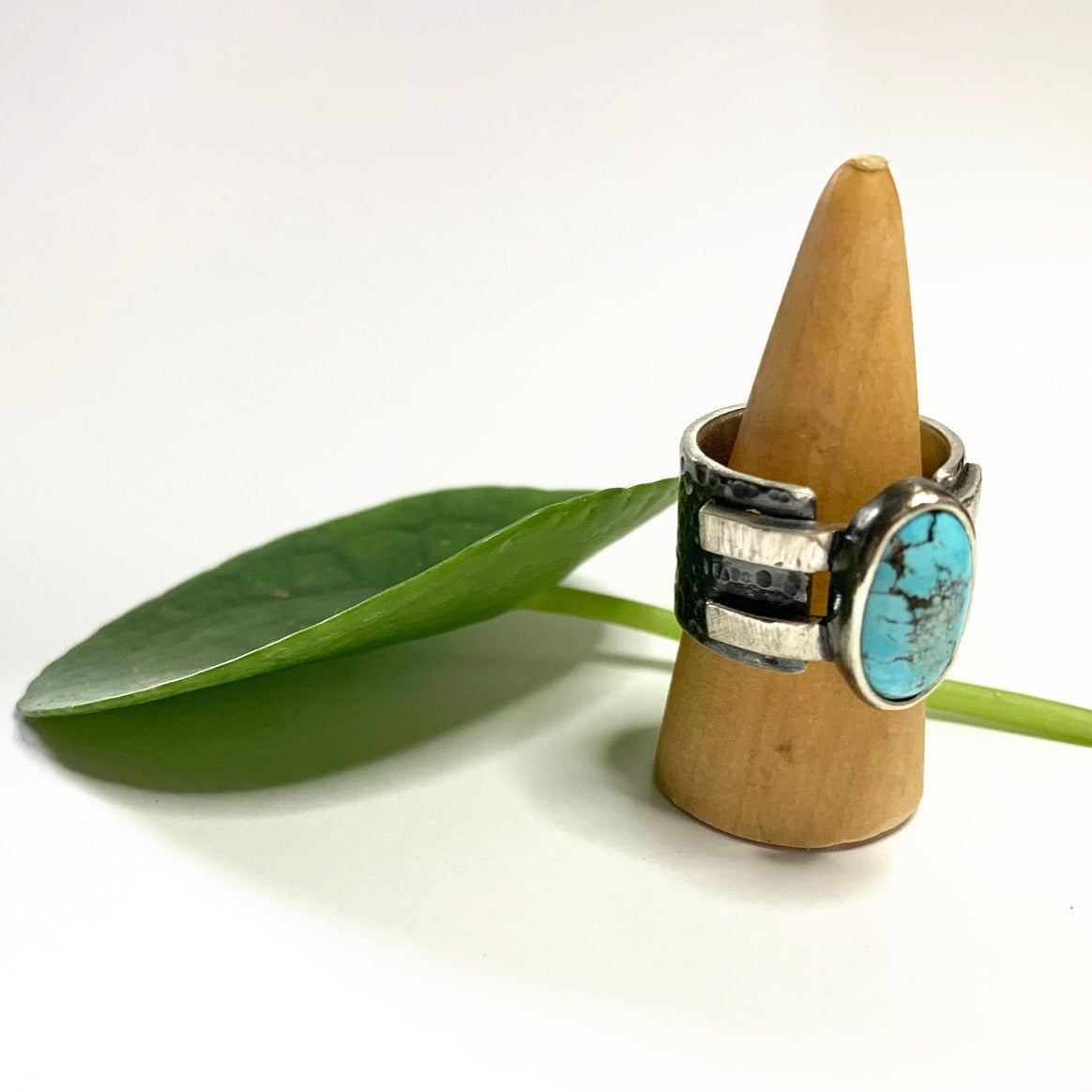 Bague en argent épaisse et martelée, inspirée du design des bracelets de force, sertie d'une turquoise d'Iran. Le serti repose sur deux bandes d'argent soudées, intégrées dans la continuité du jonc, assurant ainsi sa fermeture. Taille 59, vue de profil.