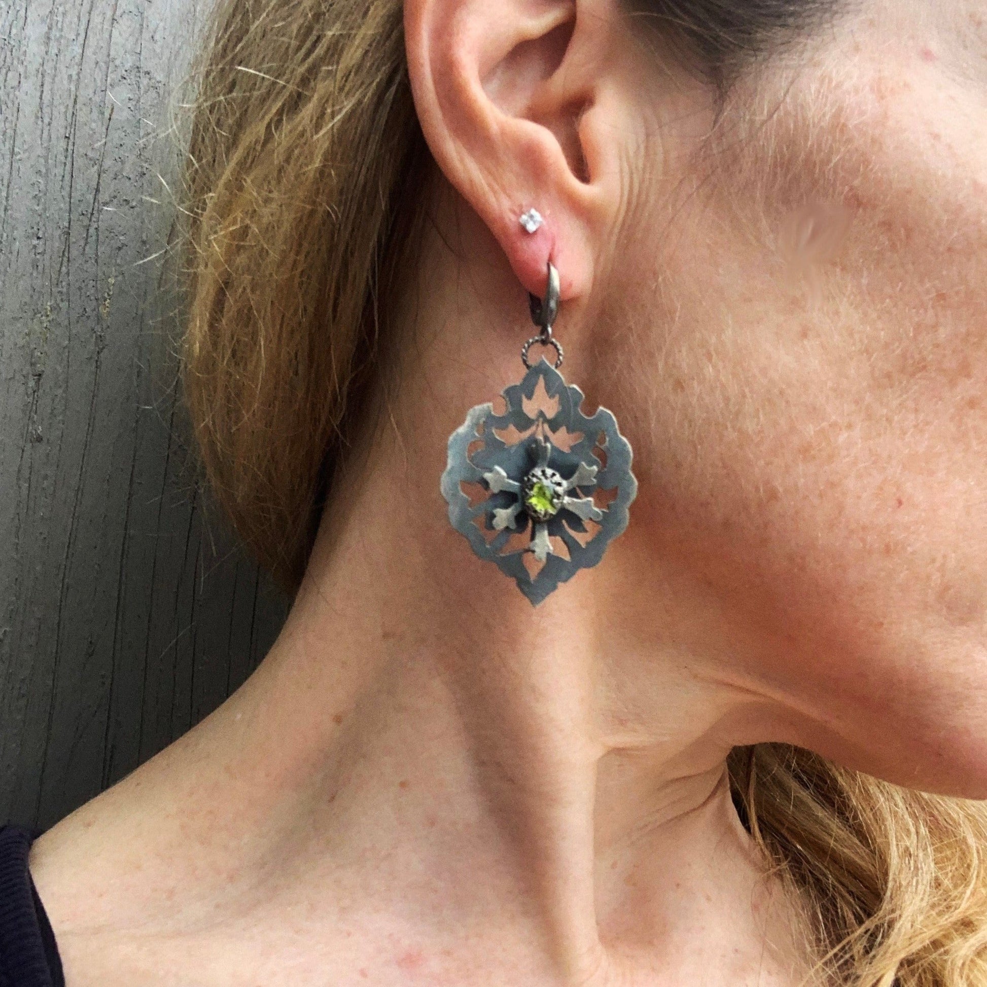 Ces boucles en argent sont constituées de deux plaques superposées et soudées avec un écart afin que la fleur centrale soit surélevée. Au  creux de cette fleur repose un serti e vésuvianite d'un vert éclatant. Inspiré des motifs hatayi. vue portée. Crochets d'oreille à clips en argent.