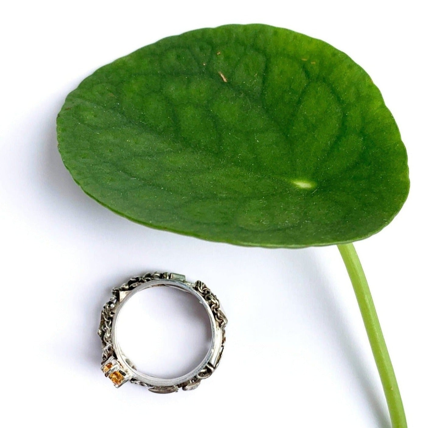 Inspirée par les couronnes de fleurs de Tahiti, cette bague évoque le Lei, symbole de l'Aloha hawaïen. Elle se compose de deux joncs : un petit en taille 62 avec une citrine de 5 mm, porté côté main, et un jonc plus large pour le pouce, constitué de morceaux d'argent travaillés. Les deux joncs sont reliés par un pont en forme de tige de plante, Vue de dessus.