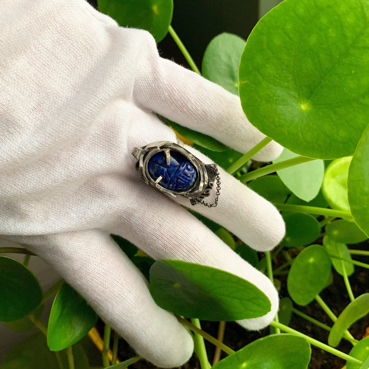 Bague en argent forgée à partir de débris modelés et agencés sans transformation, formant une carapace autour d'un lapis-lazuli sculpté en scarabée. Vue portée.